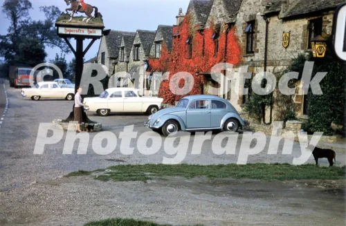 Hopcroft’s Holt Hotel in Steeple Aston with traditional stone buildings and parked 1950s cars, 1957