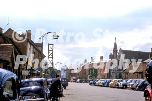 Rother Street in Stratford-upon-Avon in the 1950s showing parked cars, shopfronts and Holy Trinity Church in the distance