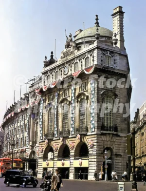 A 1950s colour photo of the County Fire Office building in Piccadilly Circus, London, featuring ornate floral decorations and bunting for the 1953 Coronation.