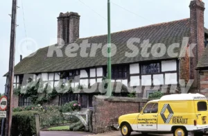 A 1970s view of a historic timber-framed house in Mayfield featuring a yellow Renault 4 service van from Marchants of Tunbridge Wells.