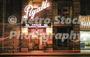 A 1950s colour photo of the Pigalle Restaurant at 190–196 Piccadilly in London, featuring the restaurant's entrance with signs for Woolf Phillips and his Orchestra and Yana.