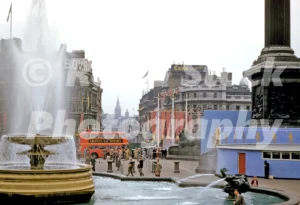 A 1950s colour photo of Trafalgar Square in 1953, showing the temporary blue coronation grandstands and festive decorations.