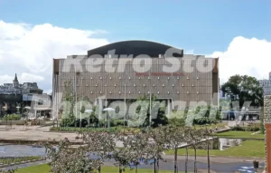 A 1950s colour photo of the rear exterior of the Royal Festival Hall on London's South Bank c1953, showing a cleared gravel landscape where the Festival of Britain structures once stood.