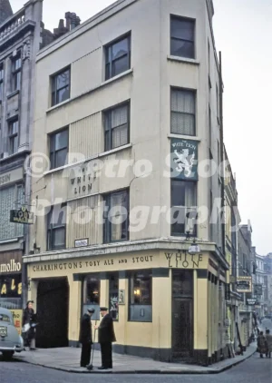 A 1950s colour photo of The White Lion pub at the corner of Brook Street and Gilbert Street in London, featuring traditional Charrington's signage.