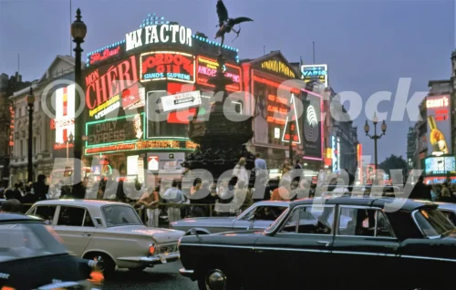 A 1960s colour photo of the glowing neon advertisements at Piccadilly Circus with evening traffic and crowds in 1969.