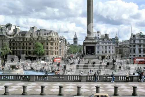 1980s photo of Trafalgar Square in London, with Nelson’s Column, the fountains, crowds of people and Big Ben visible down Whitehall.