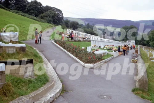 old photo of the Aberfan Disaster Memorial in Wales in 1971 with terraced graves, flowers and visitors walking through the cemetery