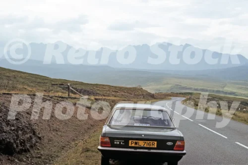 Vintage 1977 photo of a Ford Cortina 1.3L on the Isle of Skye with the Cuillin hills in the distance and a Gates Group Ford sticker in the rear window.