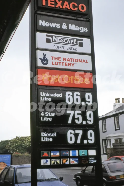 Texaco petrol station sign in the 1990s showing fuel prices, National Lottery, Post Office, Nescafe Coffee Break and News and Mags panels