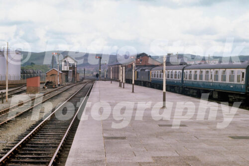 old photo of Aberystwyth Station in Wales in the 1970s with a train at the platform, semaphore signals and the signal box