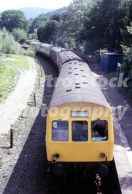 1970s view of a British Rail diesel multiple unit at Betws-y-Coed station in Wales with miniature railway tracks beside the platform