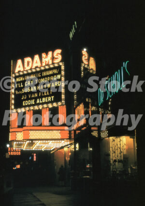 A 1950s color photo of the glowing Adams Theatre neon marquee and a green Dr. Scholl's sign in Detroit in 1955.
