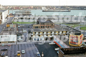 A 1960s color photo of the Cadillac House Motel and Paul's Auto Wash with a Cleveland-Cliffs freighter on the Detroit River in 1962.