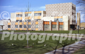 A 1960s color photo of the C.S. Mott Library in Flint, Michigan, featuring mid-century modern architecture with orange panels and decorative patterned stonework.