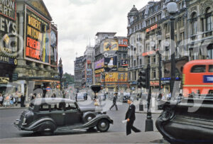 A 1950s colour photo of Piccadilly Circus in London, featuring the London Pavilion displaying a large film billboard for Robert Mitchum in Foreign Intrigue.