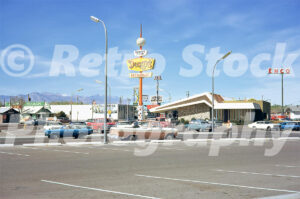 A 1970s color photo of a Denny's Restaurant with a Googie-style neon sign and snow-capped mountains in Las Vegas in 1972.