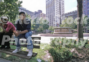 A 1980s color photo of two men sitting on a park bench in front of the Edison Memorial Fountain in Grand Circus Park in 1980.