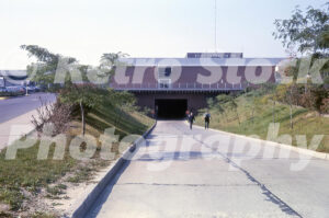 A 1960s color photo of the underground delivery tunnel entrance at Northland Center in Southfield, Michigan, featuring the Hudson's building and workers on the service ramp.
