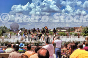 Alt Text A 1980s color photo of a live African drumming and dance performance on the World Showcase promenade at Epcot Center in Florida, with Spaceship Earth and the Mexico pavilion visible across the lagoon.