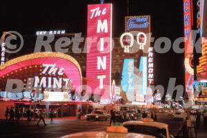 A 1960s colour photo of the towering red neon sign for The Mint and the blue Fremont Hotel sign at night in Las Vegas in 1960s.