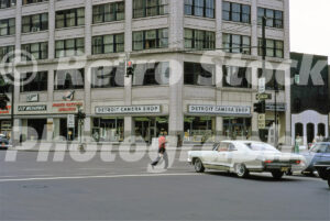 A 1980s color photo of a white Pontiac Catalina driving past the Detroit Camera Shop in the Gabriel Richard Building on Michigan Avenue in 1980.