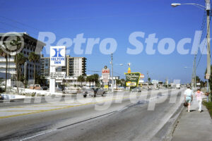 A 1980s color photo of Gulf Blvd in St. Pete Beach, showing pedestrians on the sidewalk, a large Hilton Inn sign with a disco advertisement, and various roadside businesses including Lum's and a Holiday Inn.