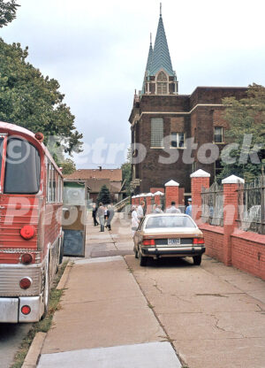 A 1980s color photo of people boarding a red bus outside the Holy Cross Hungarian Church on South Street in 1987.