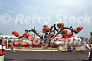 A 1970s color photo of the Monster flat ride at Kings Dominion in Virginia, featuring black rotating arms and red passenger pods under a bright sky.