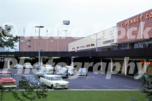 A 1960s color photo of the J.C. Penney Co. storefront and a row of shops at Lloyd Center in Portland, Oregon, featuring vintage cars and mid-century architecture.