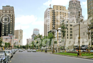 A 1980s color photo of classic cars and the Hotel Wolverine sign viewed from the intersection of State Street and Washington Boulevard in Detroit, Michigan in 1980.