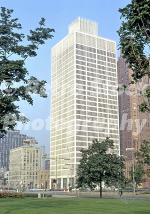 A 1960s color photo of the white Minoru Yamasaki-designed One Woodward Avenue building rising above a green lawn in Detroit, Michigan in 1967.