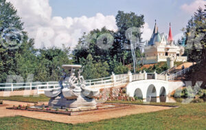 A 1950s color photo of the white fairy tale castle at Story Land in Glen, New Hampshire, featuring a white arched bridge and an ornate stone fountain in the foreground.