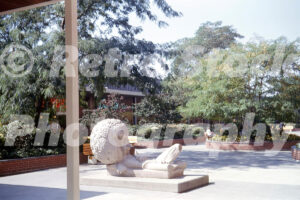 A 1960s color photo of Marshall Fredericks' "The Lion and Mouse" sculpture at Eastland Center in Harper Woods, Michigan, featuring the large reclining lion and landscaped garden courts.
