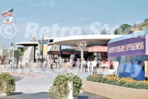 A 1970s color photo of the entrance plaza at Universal Studios Hollywood in California, featuring a large purple and blue "Universal Studios" sign, circular white shade structures, and guests in vintage summer attire.