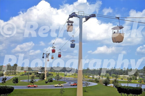 A 1970s color photo of the Skyway gondolas passing over the winding tracks of the Tomorrowland Speedway at Walt Disney World in Orlando, Florida.
