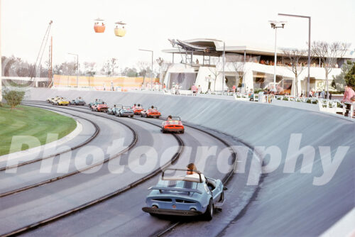 x A 1970s color photo of race cars on the Tomorrowland Speedway with Skyway gondolas overhead at Walt Disney World in Orlando, Florida.