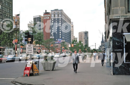 A 1960s color photo of pedestrians walking along the sidewalk of Washington Boulevard at the corner of State Street in Detroit, Michigan in 1963.