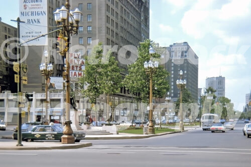 A 1960s color photo of Washington Boulevard with ornate streetlamps, a Checker Cab, and the Columbus statue looking toward Grand Circus Park in Detroit, Michigan in 1967.