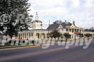 A 1970s colour photo of the white colonial-style Zehnder's Restaurant in Frankenmuth, Michigan, featuring its iconic neon sign and a red pickup truck in the parking lot.