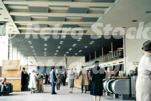 International Arrivals hall at Heathrow Airport Terminal 2 with passengers and Barclays Bank counter, 1960.