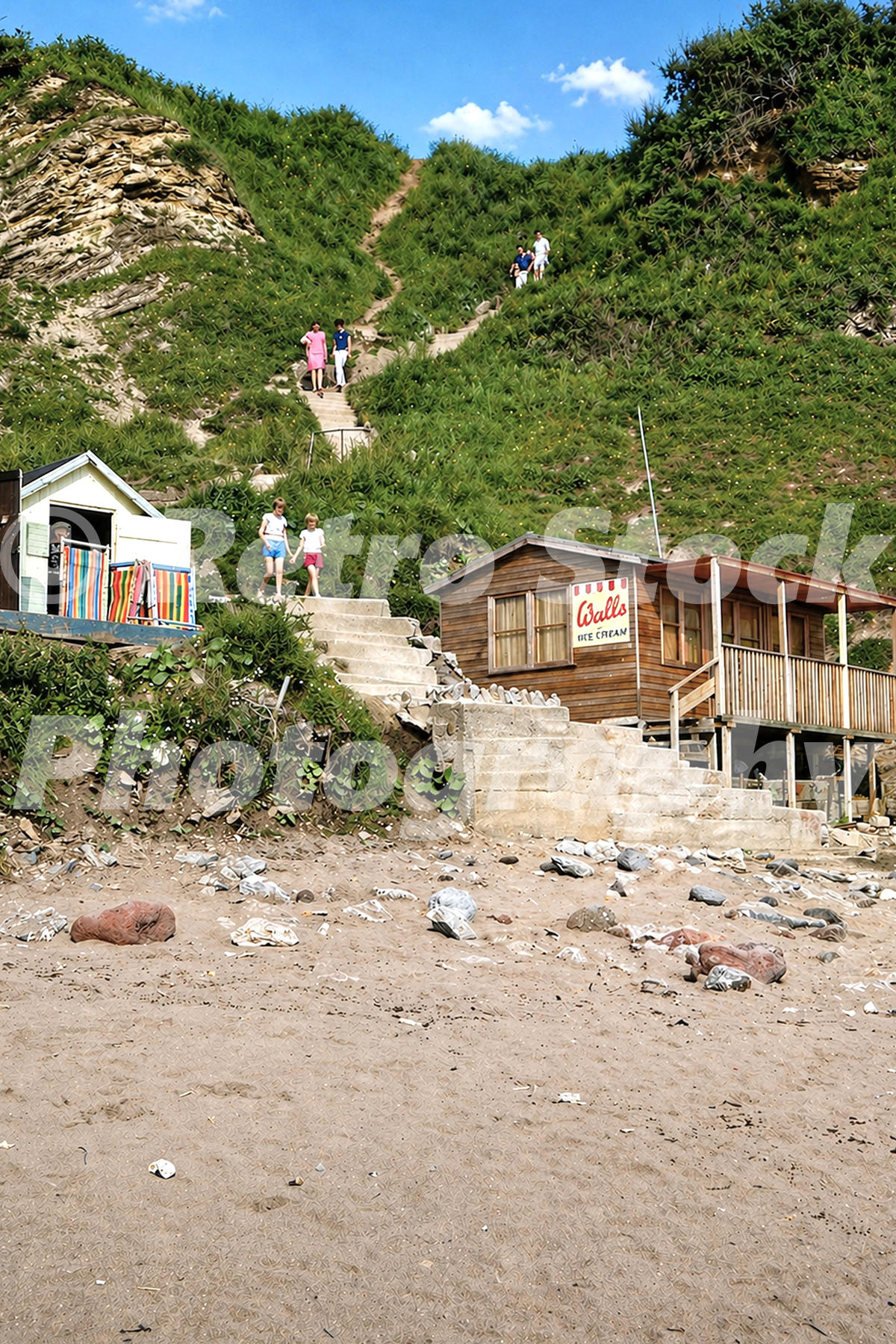 Path from Pontins Dolphin Holiday Camp to the beach at Brixham in the 1960s with cliff steps, holidaymakers and a beach hut with Walls sign
