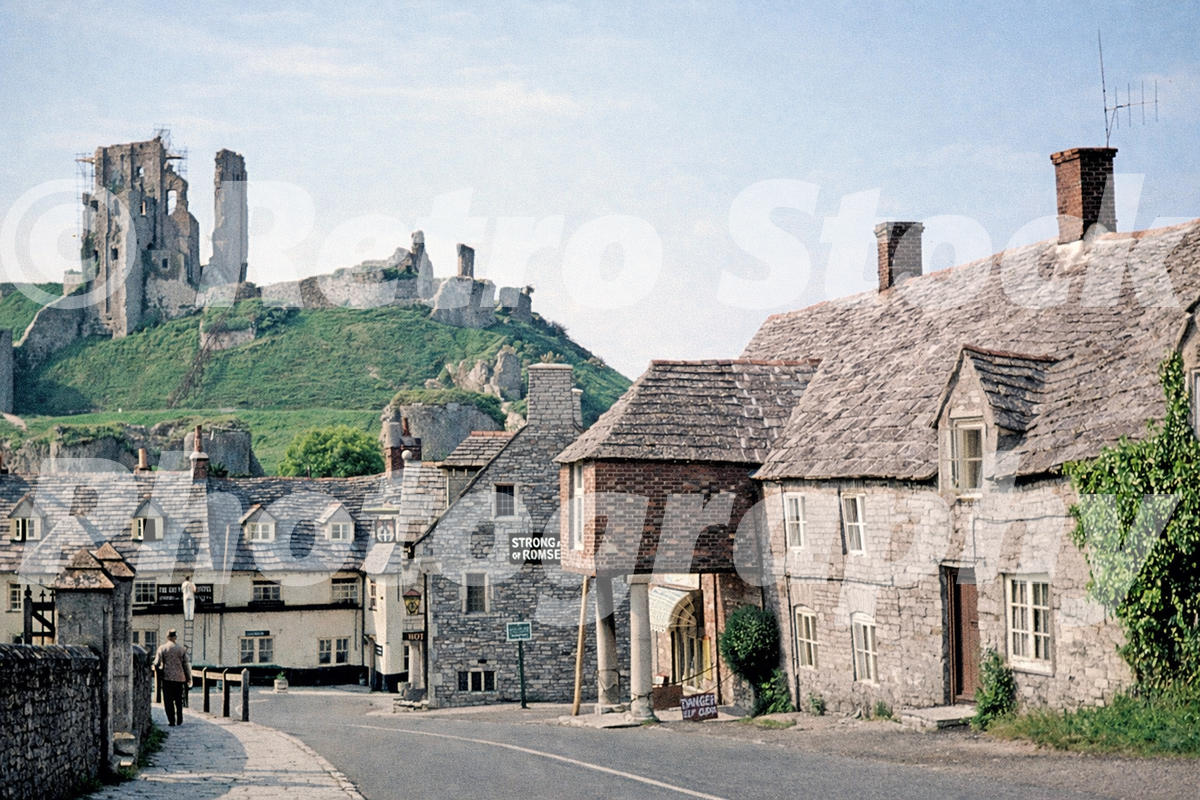 1960s view of Corfe Castle in Dorset, with village cottages and the ruined castle on the hill behind.