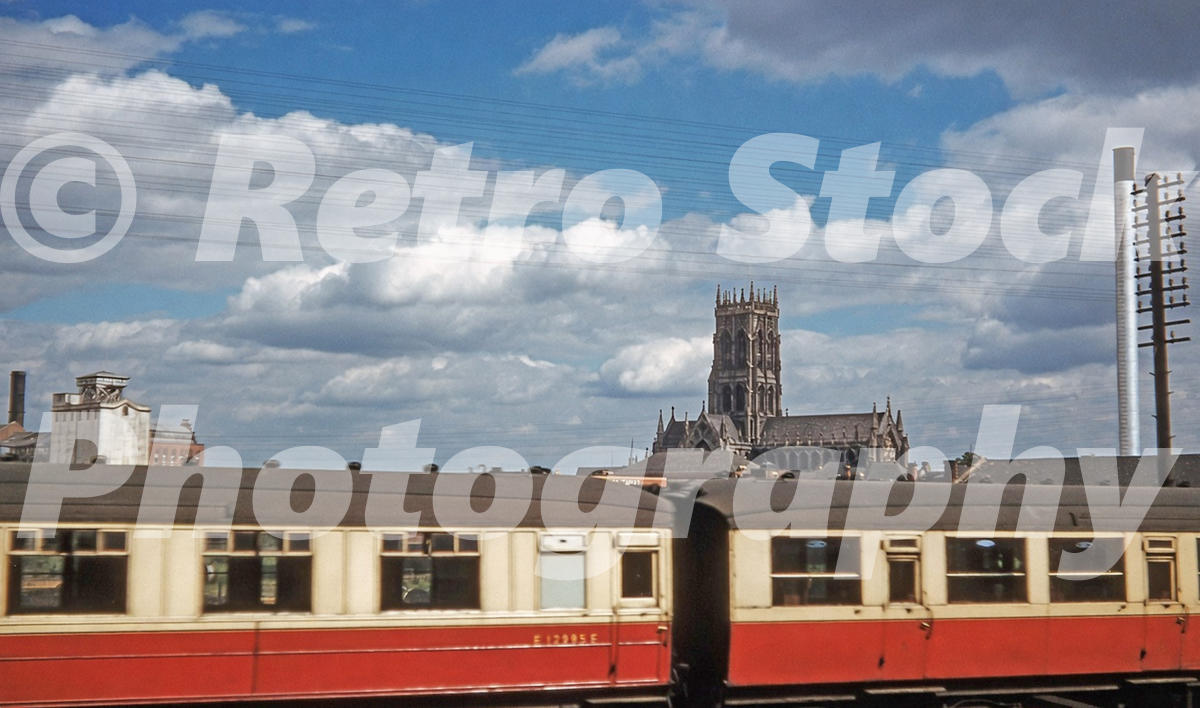 1950s view of Doncaster Minster in Yorkshire behind a passing blood and custard railway carriage with telegraph wires overhead