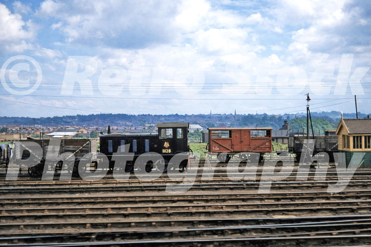 1950s photo of Drewry diesel shunter 11128 at Ipswich, standing in a railway yard among wagons, sidings and lineside huts.