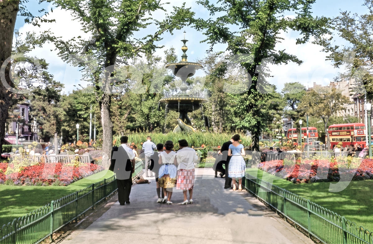 1960s view of Old Steine Gardens in Brighton with the Victoria Fountain, flower beds, visitors and red buses.