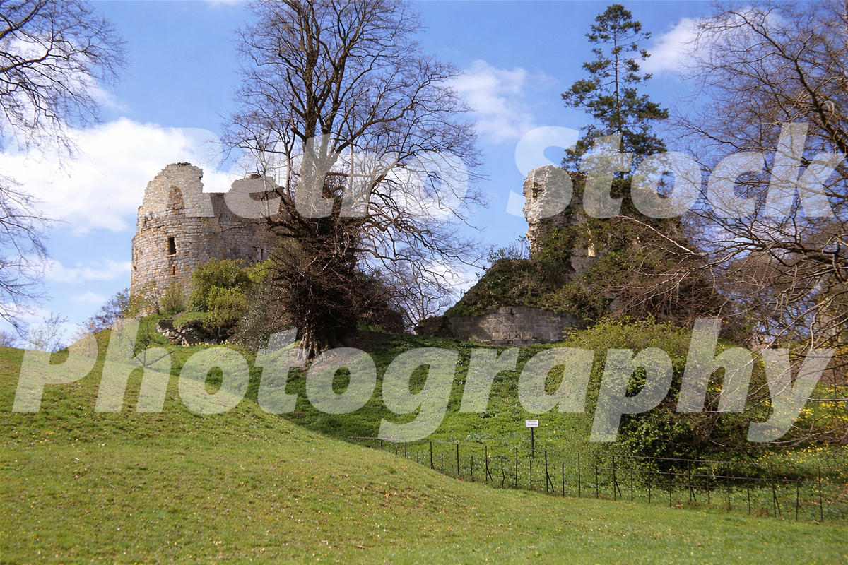 1950s view of the ruined old Hawarden Castle in Flintshire, Wales, with stone towers, trees and grassy slopes.