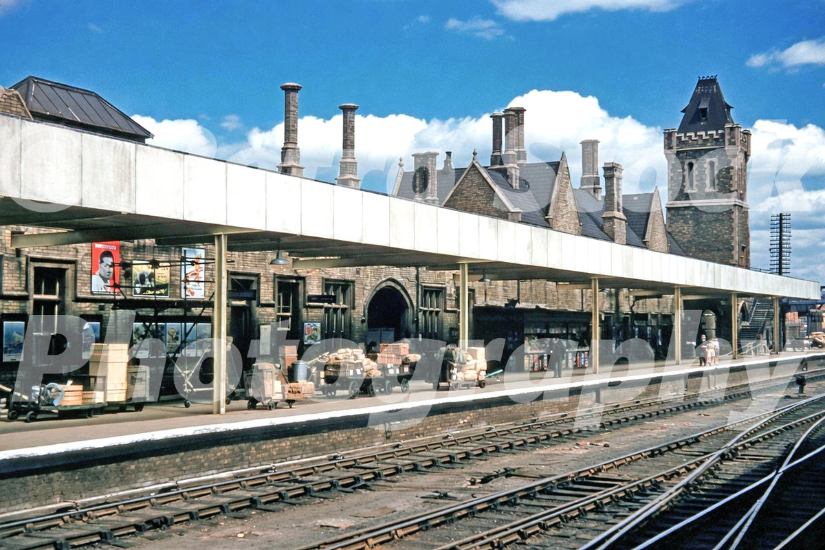 1950s view of Lincoln railway station with platform buildings, railway tracks, luggage trolleys and parcels.