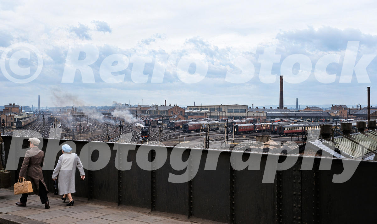 1950s elevated view from North Bridge Road in Doncaster looking south over the station approaches, sidings, coaching stock and railway works with steam drifting across the scene