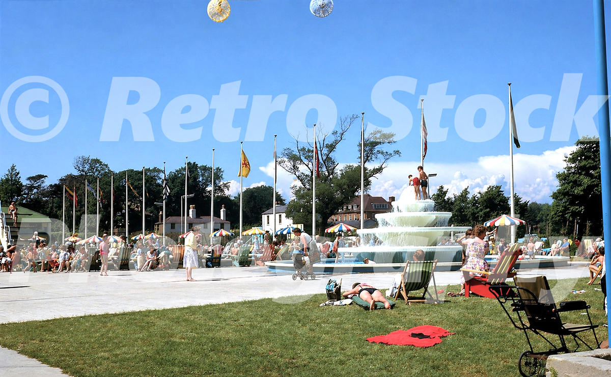 1960s photo of holidaymakers relaxing around a large fountain at Butlins Bognor Regis holiday camp on a sunny day