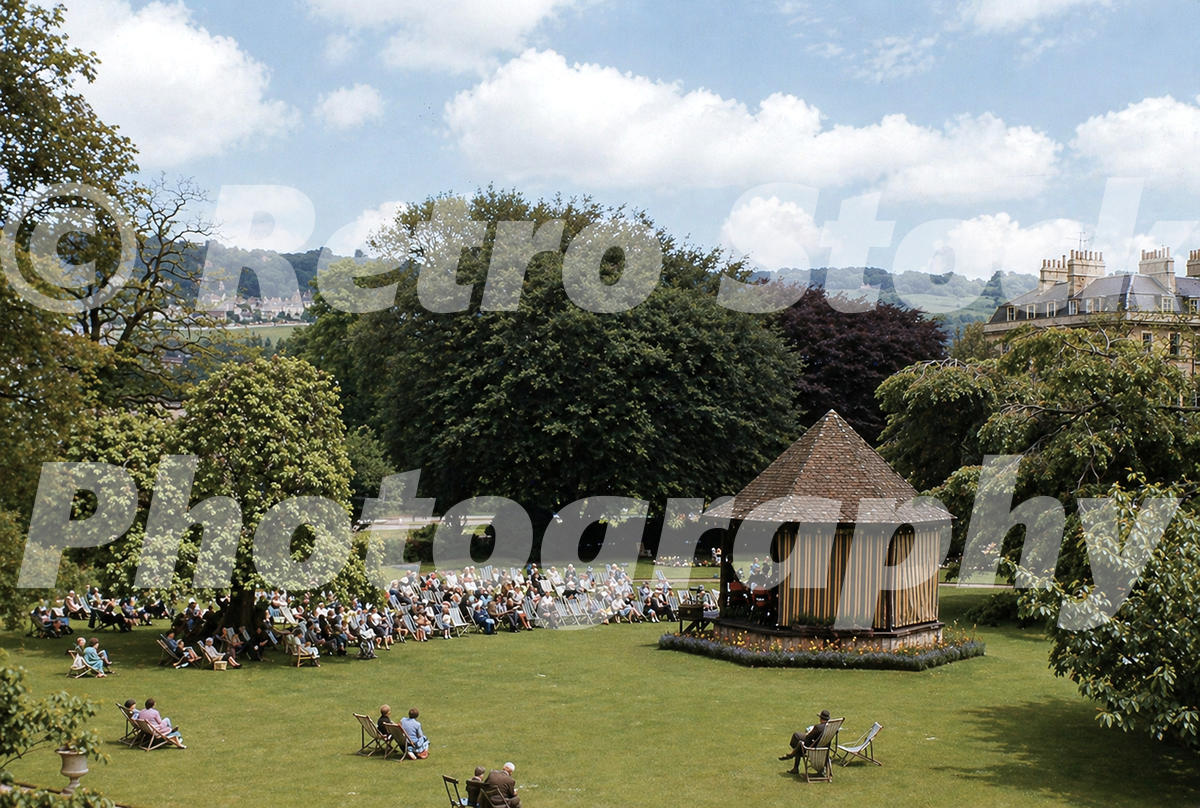 1950s view from Pierrepont Street across Parade Gardens in Bath, with visitors in deckchairs around the Victorian bandstand.